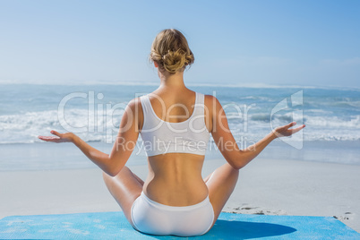 Fit woman sitting in lotus pose on the beach