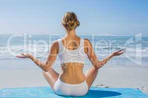 Fit woman sitting in lotus pose on the beach