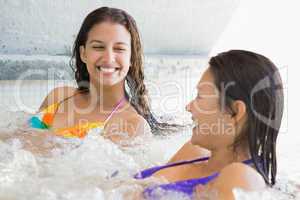 Smiling friends in bikinis relaxing in hot tub