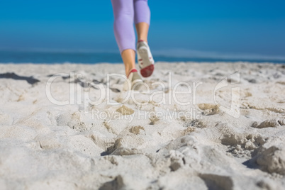 Sporty womans feet jogging on the sand