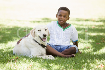 Cute little boy sitting with labrador dog