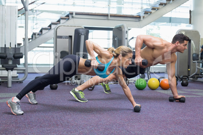 Bodybuilding man and woman holding dumbbells in plank position