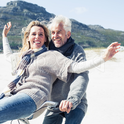 Carefree couple going on a bike ride on the beach