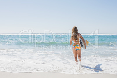 Beautiful surfer girl walking to the sea with her surfboard Beautiful surfer girl walking to the sea with her surfboard