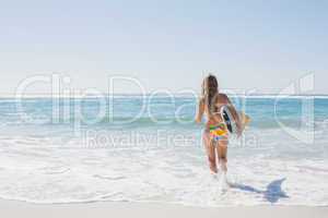 Beautiful surfer girl walking to the sea with her surfboard