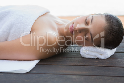 Peaceful brunette lying with eyes closed on a towel
