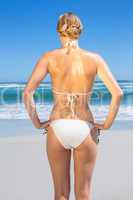 Fit woman in white bikini on the beach rear view