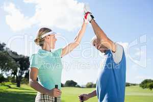 Golfing couple high fiving on the golf course