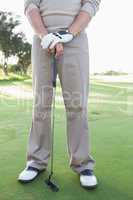 Low section of golfer standing with club