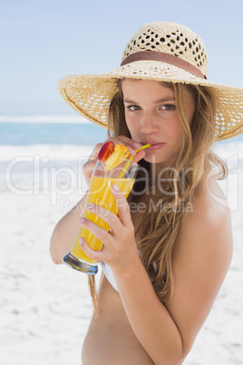 Pretty smiling blonde in bikini holding cocktail on the beach