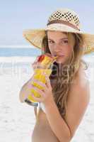 Pretty smiling blonde in bikini holding cocktail on the beach