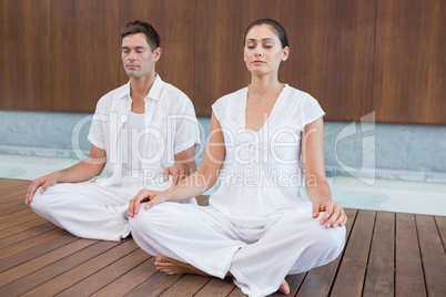 Attractive couple in white sitting in lotus pose