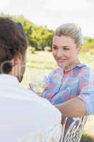 Happy young couple sitting in the garden enjoying wine together