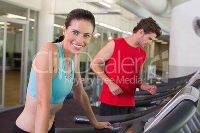 Fit happy couple running together on treadmills