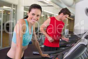 Fit happy couple running together on treadmills