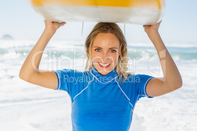 Blonde happy surfer holding her board on the beach