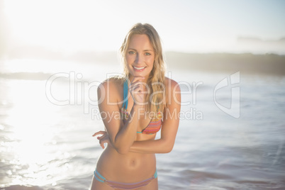 Happy blonde smiling at camera in bikini at the beach