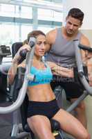 Personal trainer coaching smiling female bodybuilder using weigh