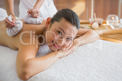 Content brunette enjoying a herbal compress massage