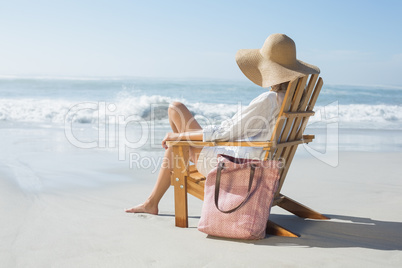 Woman sitting on wooden deck chair by the sea