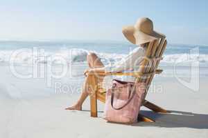 Woman sitting on wooden deck chair by the sea