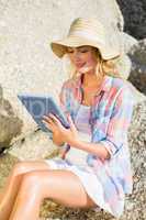 Gorgeous happy blonde using tablet pc at the beach