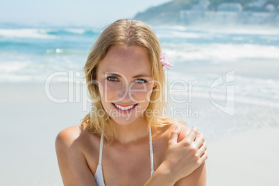 Beautiful blonde in white bikini smiling at camera on the beach