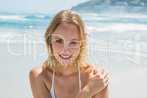 Beautiful blonde in white bikini smiling at camera on the beach