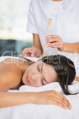 Relaxed brunette getting an ear candling treatment