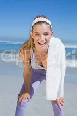 Sporty smiling blonde standing on the beach with towel