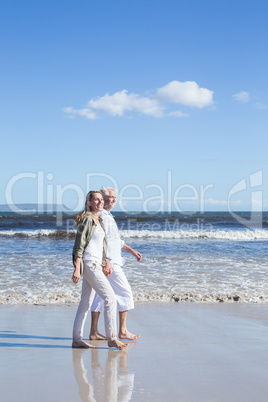 Happy couple strolling barefoot on the beach