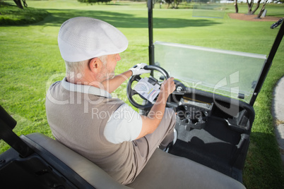 Happy golfer driving his golf buggy