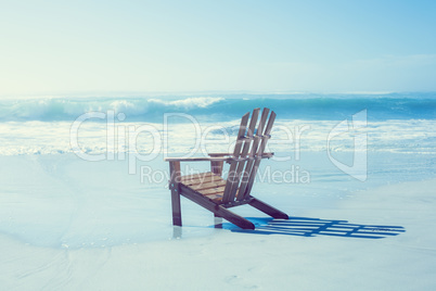 Wooden deck chair in the sand by the sea
