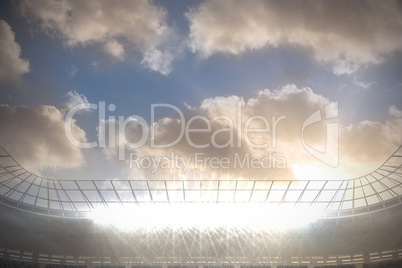 Large football stadium with spotlights under blue sky with cloud