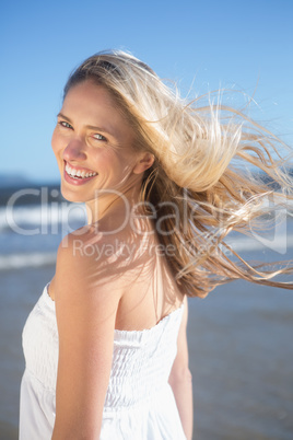 Woman in white dress smiling at camera on the beach