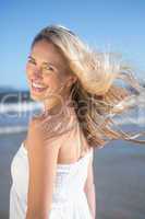 Woman in white dress smiling at camera on the beach