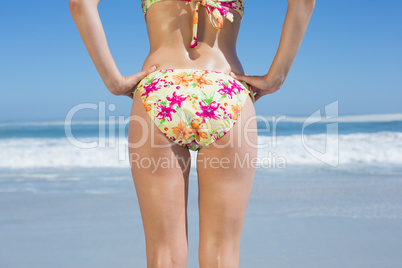 Lower rear view of fit woman in floral bikini at beach