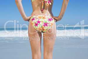 Lower rear view of fit woman in floral bikini at beach