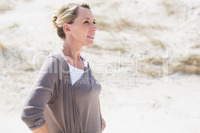 Thinking blonde woman standing on the beach