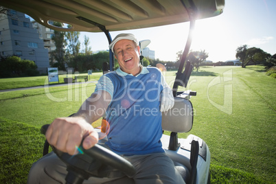 Golfer driving his golf buggy and smiling at camera