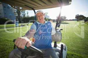 Golfer driving his golf buggy and smiling at camera
