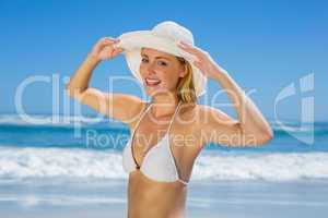 Smiling blonde in white bikini and sunhat on the beach