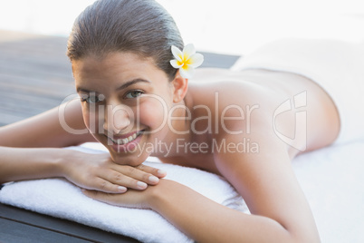 Happy brunette lying on a towel poolside