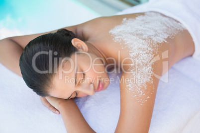 Calm brunette lying on towel with salt treatment on back