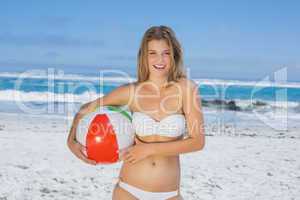 Smiling slim woman holding beach ball