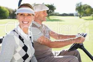 Happy golfing couple driving in their buggy