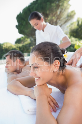 Attractive couple enjoying couples massage poolside