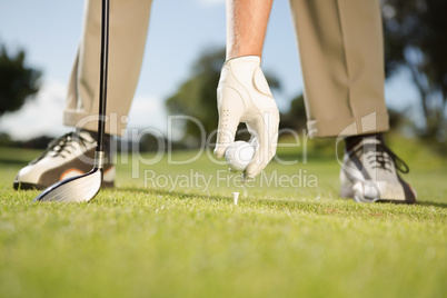 Golfer placing golf ball on tee