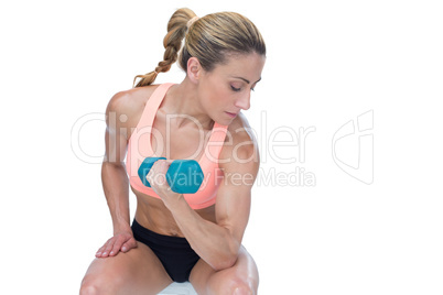 Strong woman doing bicep curl with blue dumbbell