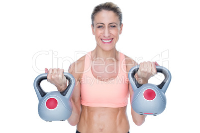 Smiling female crossfitter lifting kettlebells